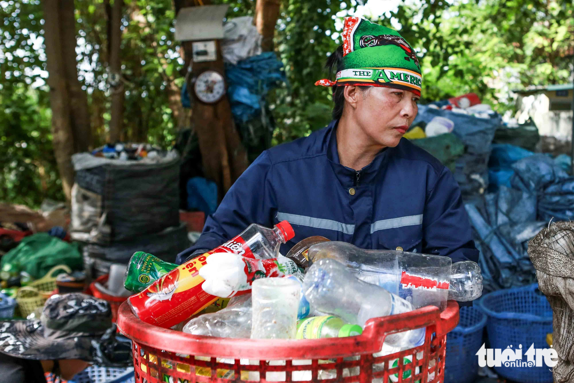 Bà Nguyễn Thị Sơn bê rổ phế liệu đã phân loại rồi cho vào một bao tải mới để bán - Ảnh: HOA NGUYỄN